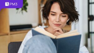 mulher branca de cabelos pretos e curtos lendo um livro de capa azul